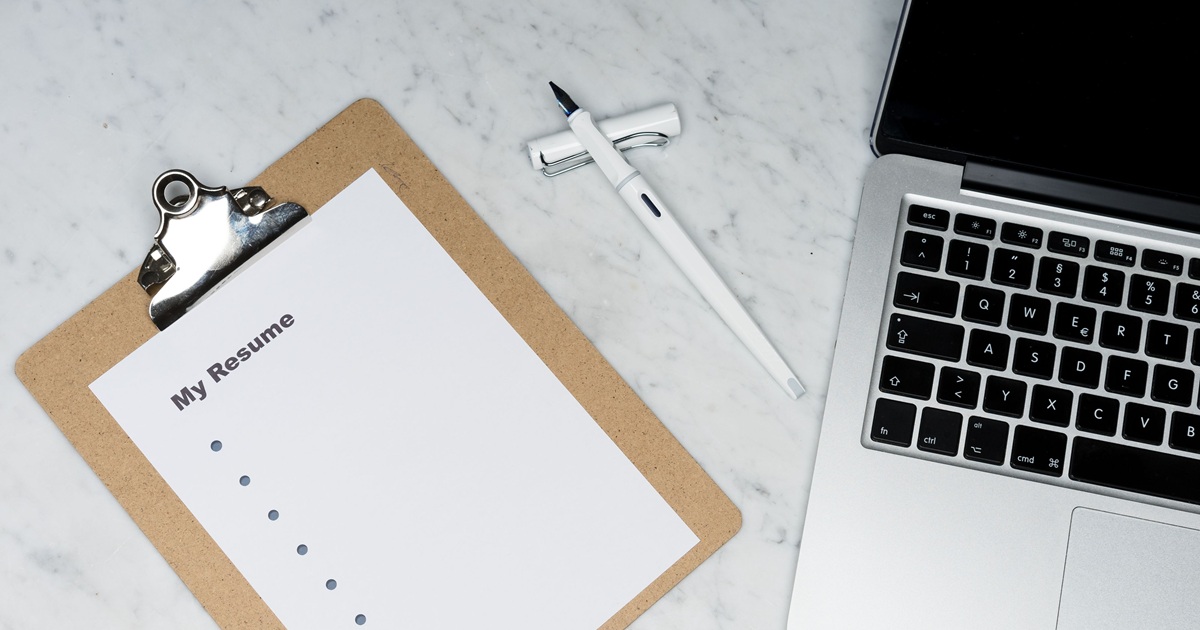 Notebook and pen on a desk beside an open laptop